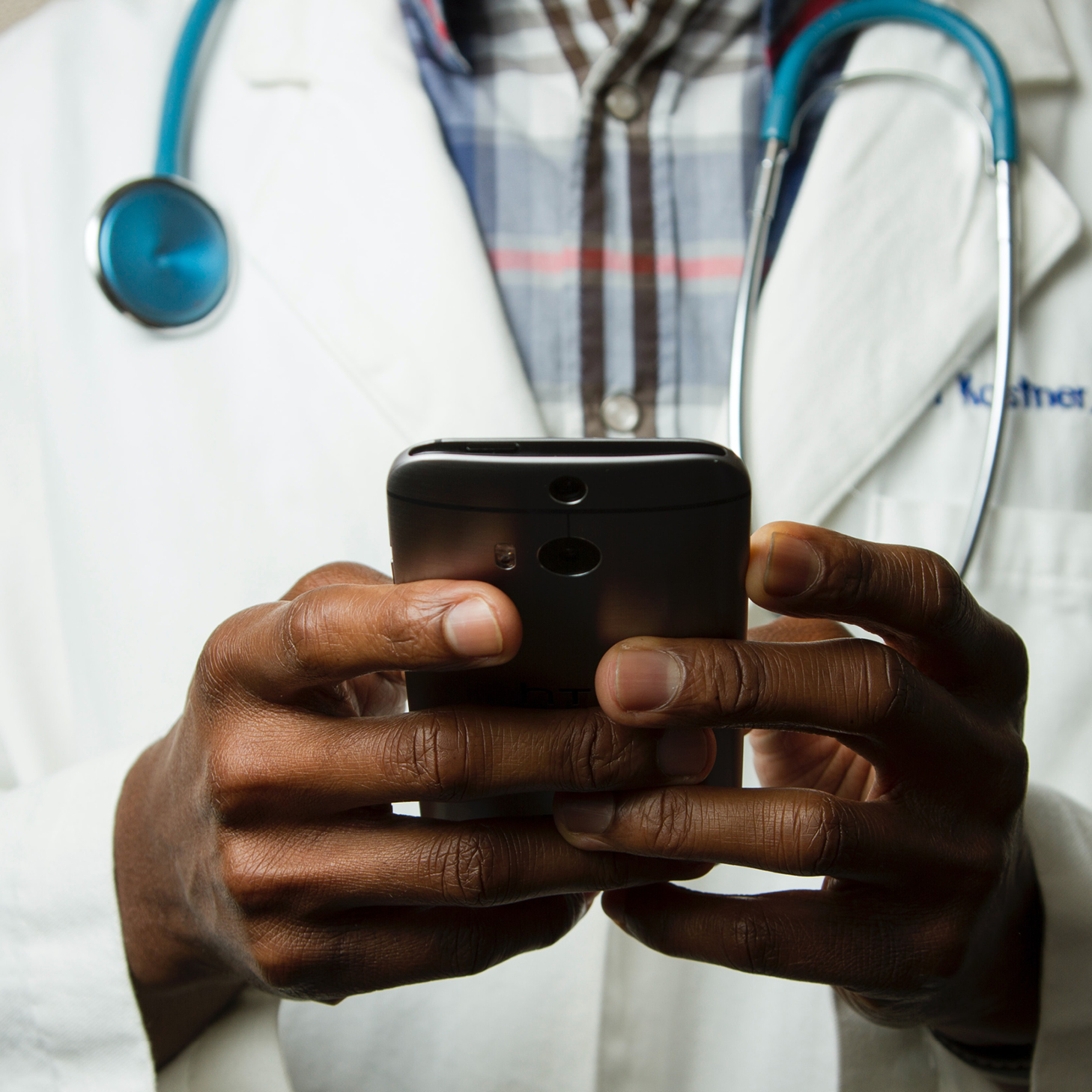 A close up image of a doctor holding a smart phone in his hands