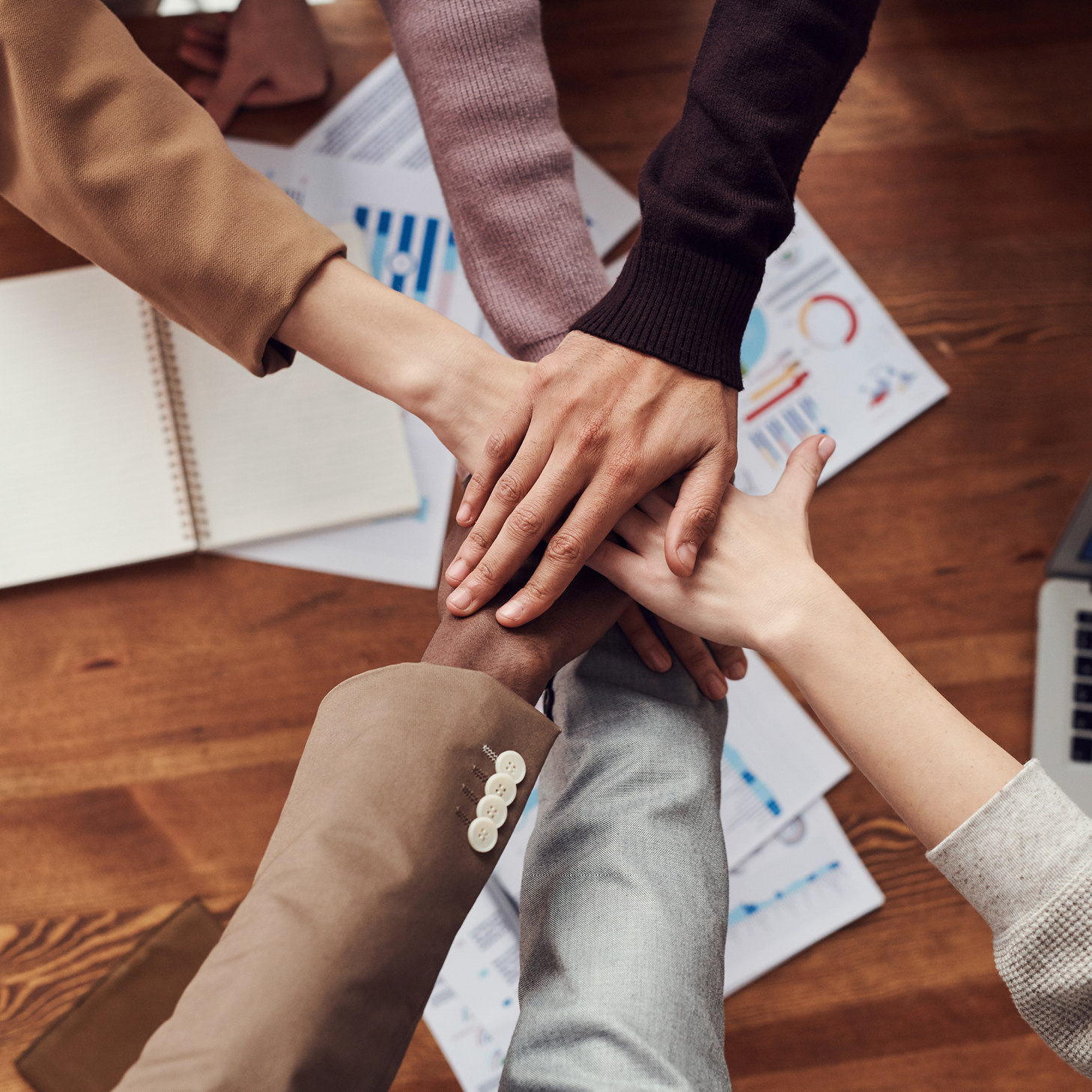 Group of people all putting their hands together in a show of teamwork