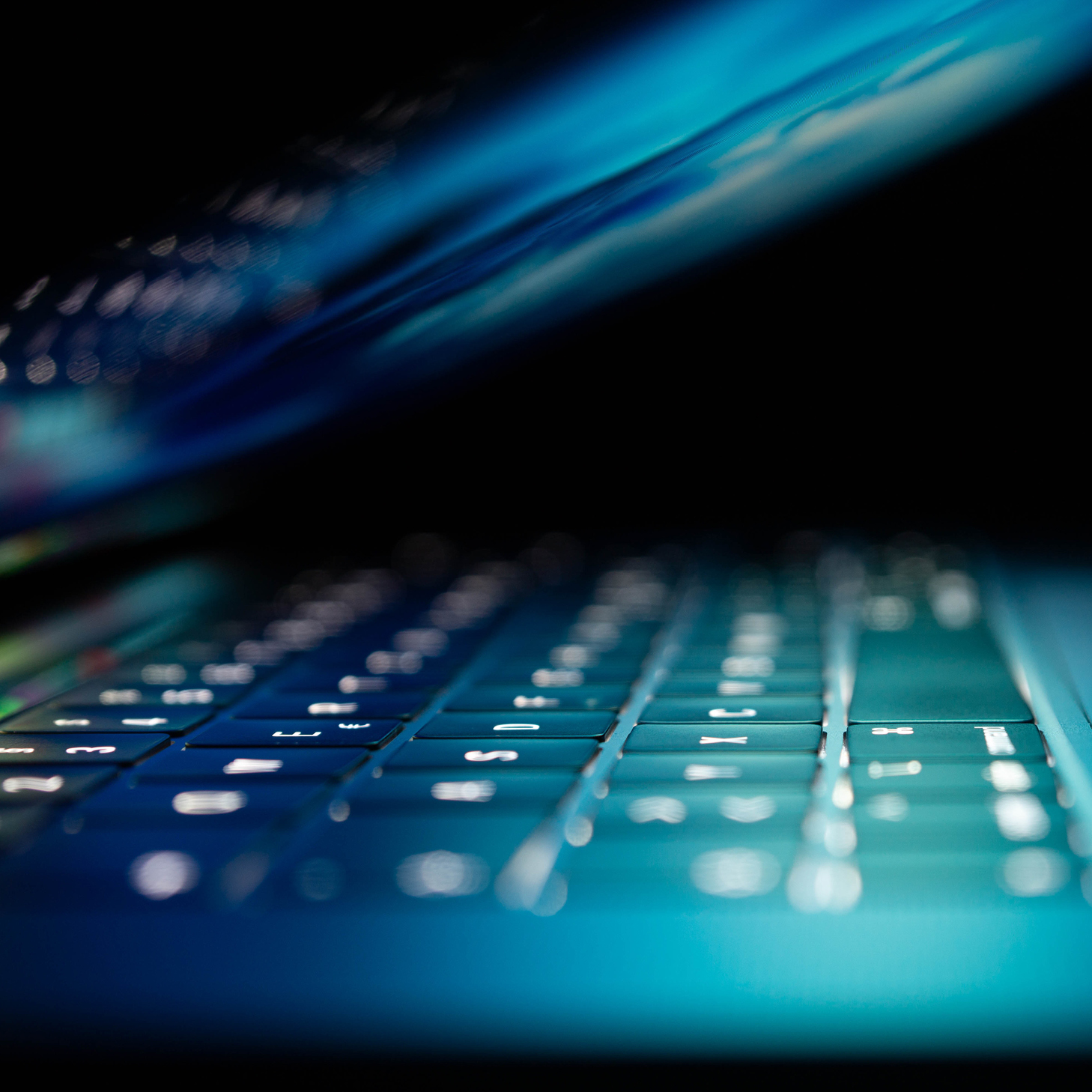 A close up of a laptop keyboard illuminated by lights