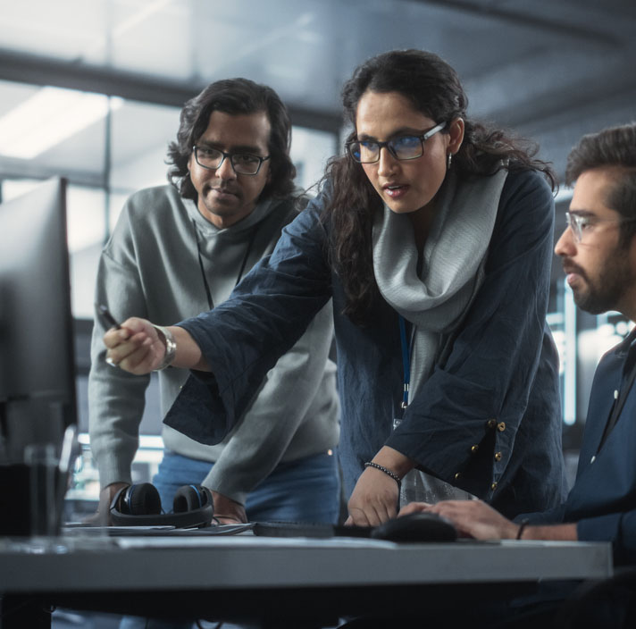 Engineers collaborating on a technical issue while analyzing data on a computer
