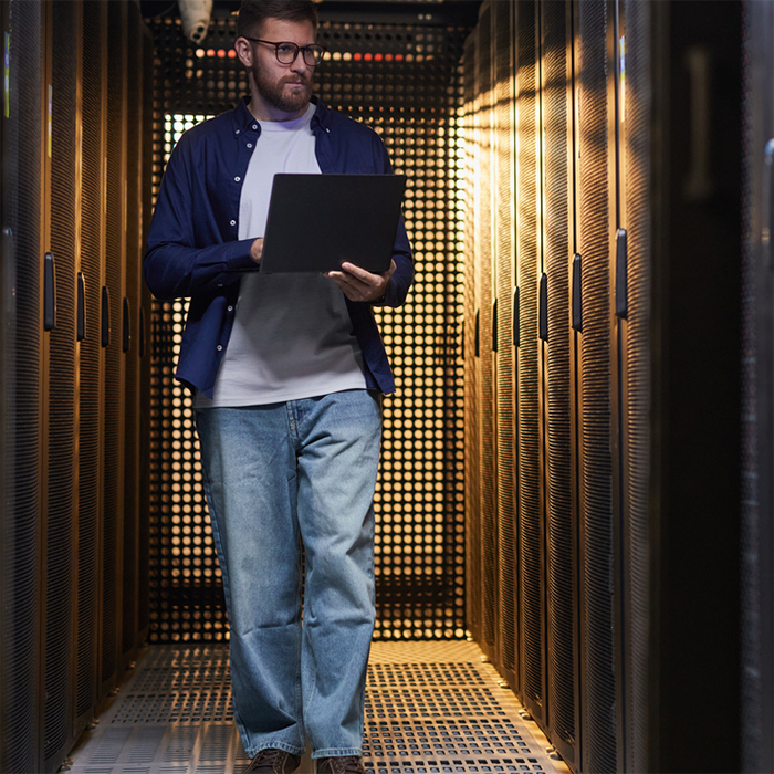 Men walking in a data center with his laptop